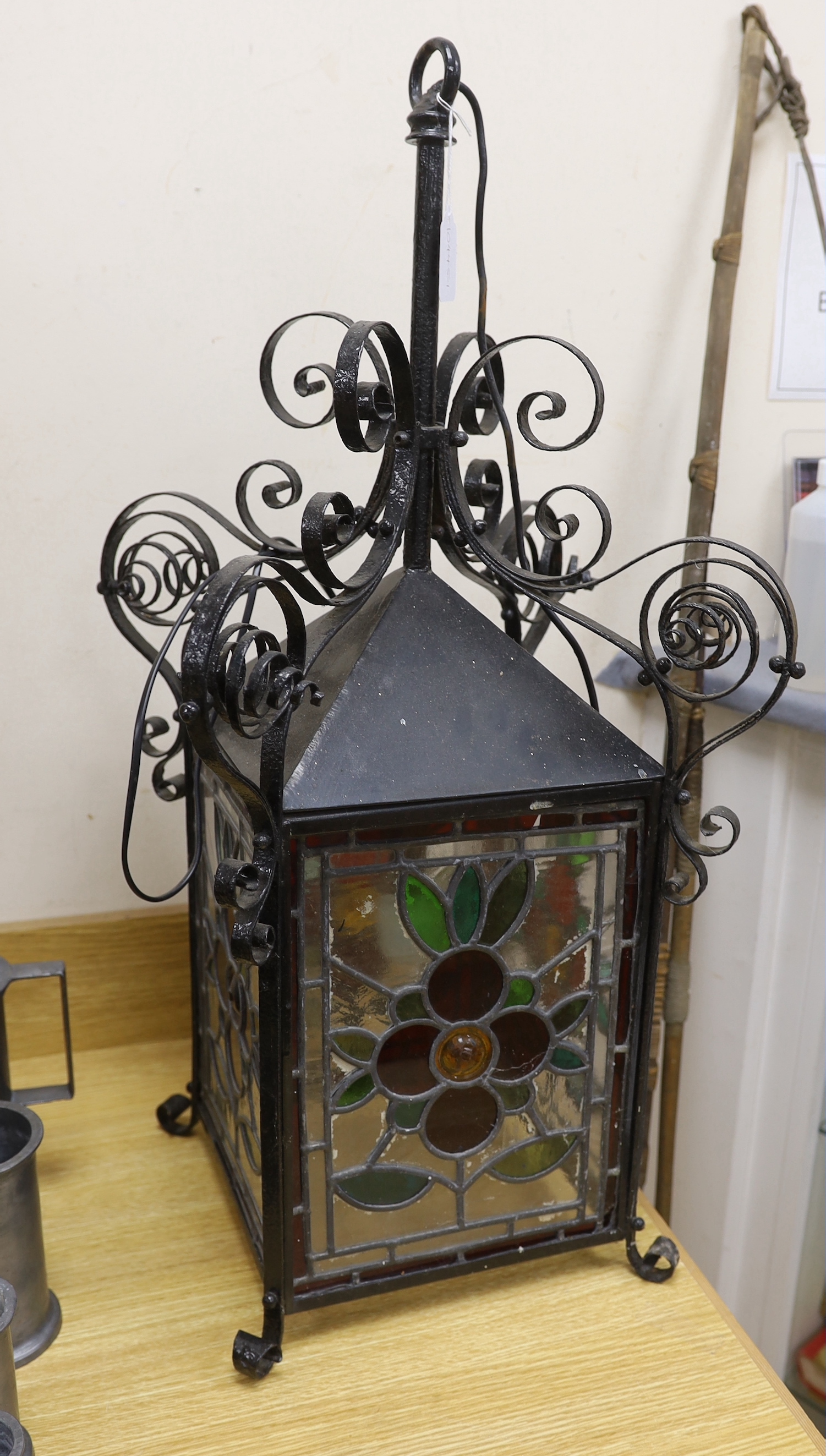 A late 19th/early 20th century Arts and Crafts style wrought iron and stained glass panelled hanging lantern, 80cms high